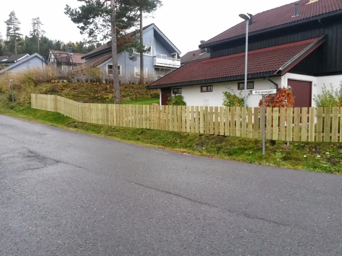 Tregjerde rundt sort hus med rødt tak